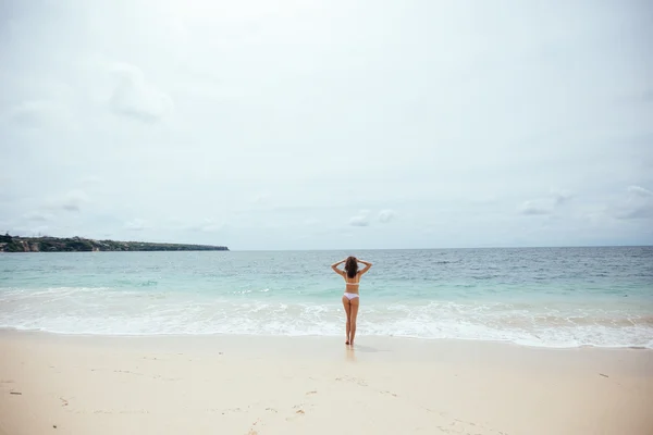 Vacker flicka i baddräkt promenader längs vyn beach.back — Stockfoto