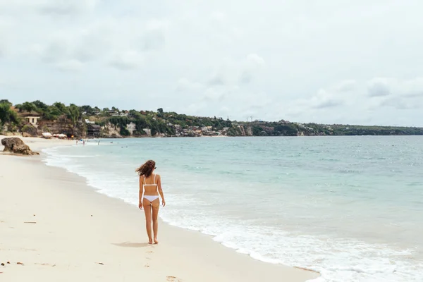 Vacker flicka i baddräkt promenader längs vyn beach.back — Stockfoto
