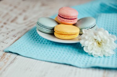 Bir plaka üzerinde mavi masa peçete ahşap ba üzerinde renkli macaroons