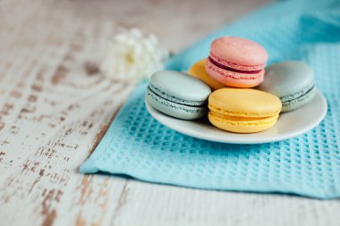 Bir plaka üzerinde mavi masa peçete ahşap ba üzerinde renkli macaroons