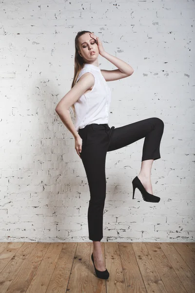 Fashion model in black trousers and white blouse posing over whi — Stock Photo, Image