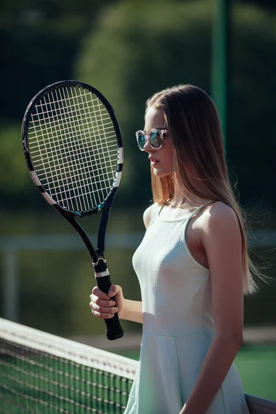 Молодая женщина играет в теннис держа ракетку. Блондинка позирует о — стоковое фото