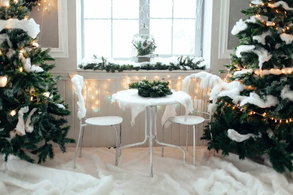 Mesa Com Duas Cadeiras Entre Árvores Natal Cobertas Neve Guirlandas — Fotografia de Stock