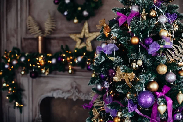 Vánoce a Nový rok zdobené luxusní interiér pokoje s dárky a novoroční strom v blízkosti krbu a pohovka ve fialových a zlatých barvách — Stock fotografie