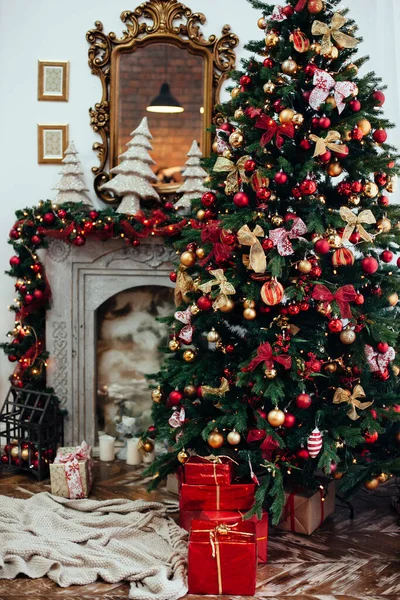 Christmas and New Year decorated interior room with presents and New year tree near fire place in red classic style — Stock Photo, Image