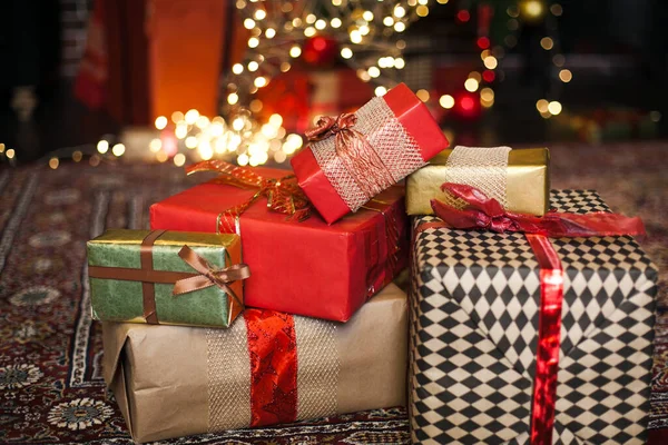 クリスマスプレゼントは ロフトで茶色と赤の紙に包まれ 背景にはクリスマスツリーのぼんやりとした光があります スペースのコピー — ストック写真