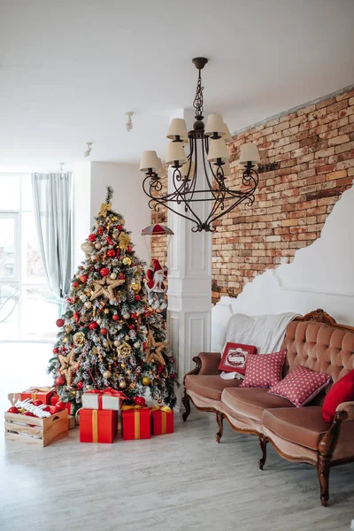 Navidad y Año Nuevo decorado habitación interior con regalos rojos y árbol de Año Nuevo y sofá marrón clásico en frente de la pared blanca. —  Fotos de Stock