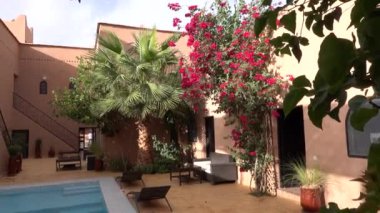 Fas, Marakeş - Ekim 2019: Geleneksel Fas 'ta avluda yüzme havuzu, Arap dizaynında kil evler ve çiçekli ağaçlar