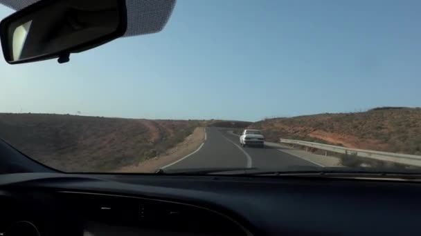 モロッコ- 10月2019:大気中の荒野と青空の間の砂漠の高速道路沿いの運転車から撮影 — ストック動画