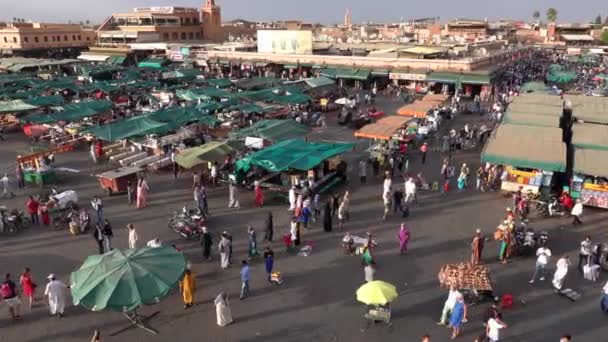 Morocco, Marrakech - October 2019: Top view of Jemaa el-Fna square at dusk with moving multids of people between market stall with green nents and umbrelas in sunset time — стокове відео