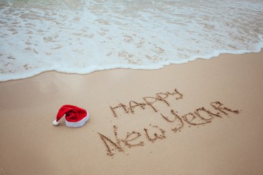 mutlu yeni yıl Noel Baba şapkası kumla yazılmış