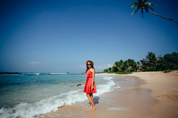 Mulher bonita elegante em vestido vermelho e chapéu de palha na praia . — Fotografia de Stock