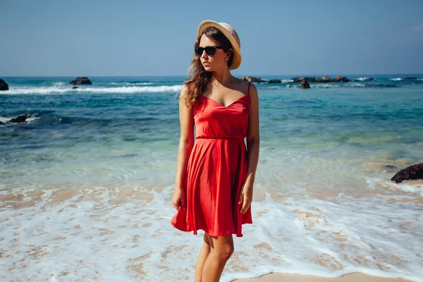 Elegant vacker kvinna i röd klänning och stråhatt på stranden. — Stockfoto