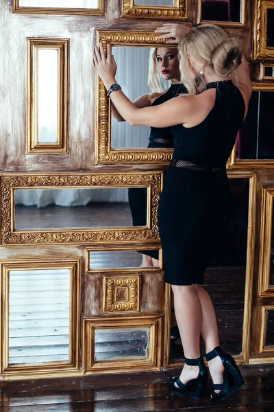 Сексуальна жінка в маленькій чорній сукні позує біля дзеркал. модна фотографія — стокове фото