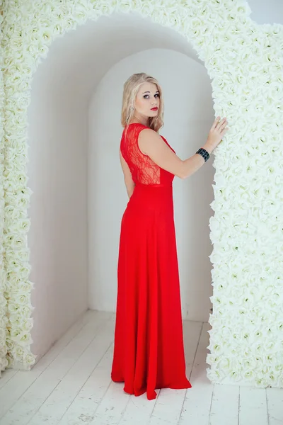 Красивая блондинка с красными губами в красном платье позируя в цветок — стоковое фото
