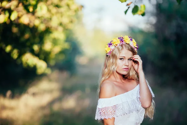 Porträtt av blond flicka klädd i vit klänning med blomma krans — Stockfoto