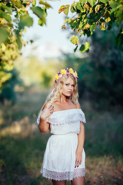 Retrato de menina loira vestindo vestido branco com coroa de flores — Fotografia de Stock