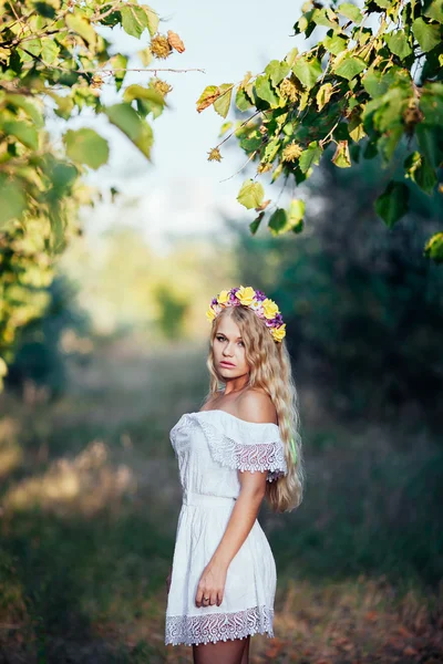 Porträtt av blond flicka klädd i vit klänning med blomma krans — Stockfoto