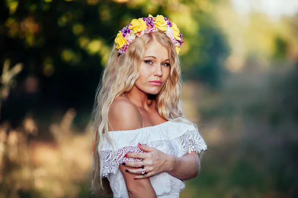 Porträtt av blond flicka klädd i vit klänning med blomma krans — Stockfoto