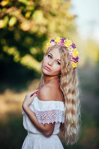 Porträtt av blond flicka klädd i vit klänning med blomma krans — Stockfoto