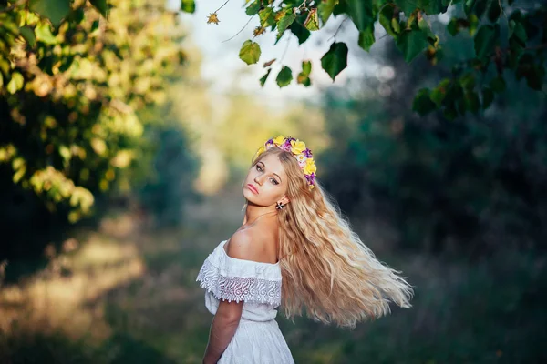 Porträtt av blond flicka klädd i vit klänning med blomma krans — Stockfoto