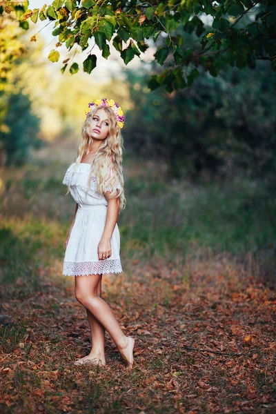 Ganzkörperporträt eines blonden Mädchens in weißem Kleid mit Blumenkranz — Stockfoto