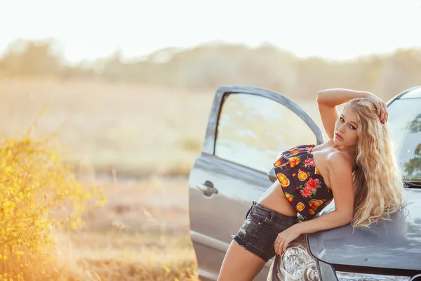 Glückliche junge Frau mit Auto - sexy reiche Fahrerin mit langen blonden Haaren — Stockfoto
