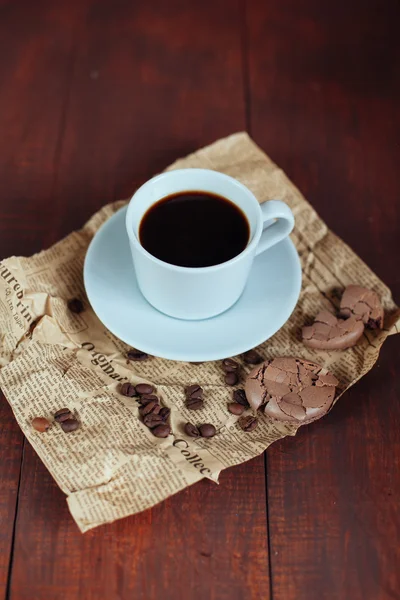 Разбитое шоколадное печенье, бобы и кофе в кружке на деревянной вкладке — стоковое фото