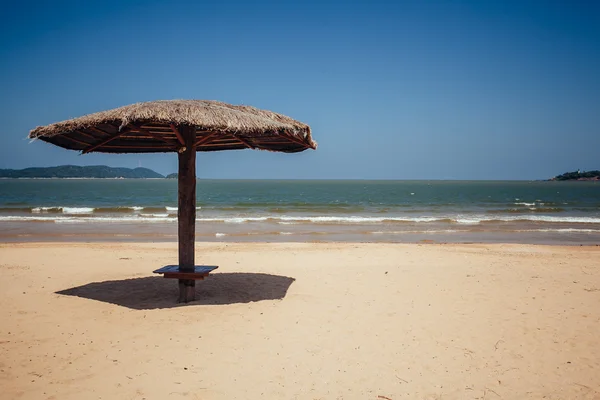Пляжный зонтик на песке рядом с тропической лагуной. Солнечные зонтики — стоковое фото