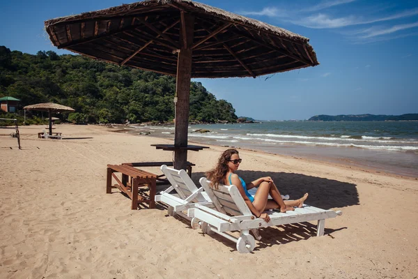 Woman on a tropical beach on deck chair under sun umbrella.woman