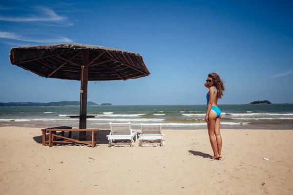 Женщина отдыхает на тропическом пляже возле шезлонга и шезлонга — стоковое фото