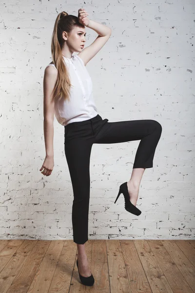 Fashion model in black trousers and white top posing over white background — Stock Photo, Image