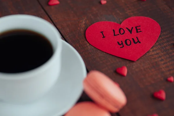 Valentines day background concept. Cup of coffee with sweets macaroons, note with words I Love you  on the wooden background. — Stock Photo, Image