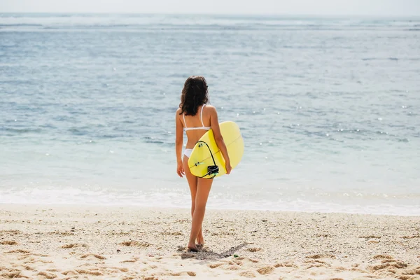 Beauitful nuori surffaaja tyttö menee aaltoja hänen surfboar — kuvapankkivalokuva