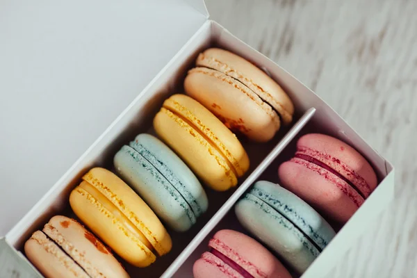 Macarrones coloridos en la caja sobre fondo blanco de madera —  Fotos de Stock