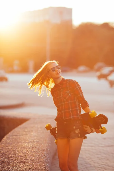 Sportovní móda dívka pózuje v létě světlo s skateboard — Stock fotografie