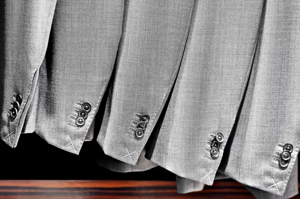 Elegantes trajes grises en una fila dentro de la tienda de trajes —  Fotos de Stock
