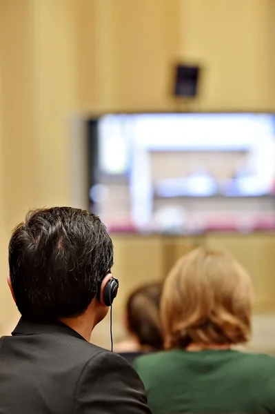 Pessoas uing fones de ouvido de tradução durante a apresentação de vídeo — Fotografia de Stock