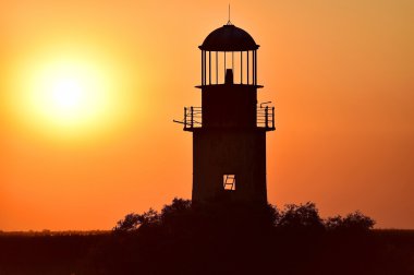 Bir nehir üzerinde günbatımında terk edilmiş deniz feneri