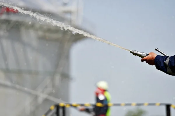 Bombero sosteniendo manguera de agua de alta presión — Foto de Stock