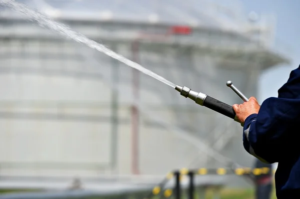 Bombero sosteniendo manguera de agua de alta presión — Foto de Stock