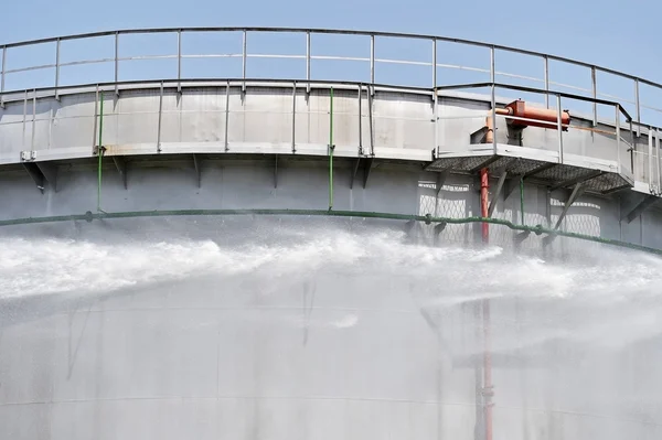 Bombero chorro de agua en el tanque de almacenamiento grande — Foto de Stock