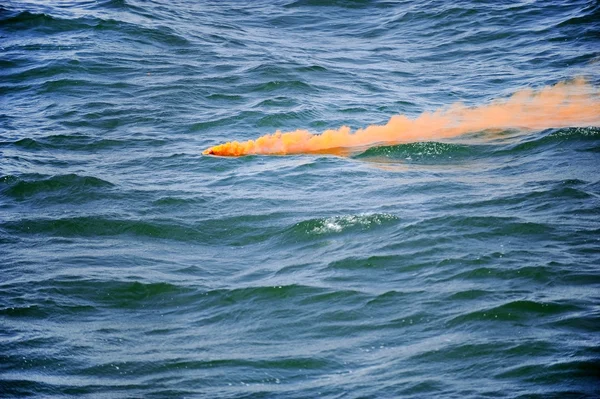 Orange smoke flare in the water