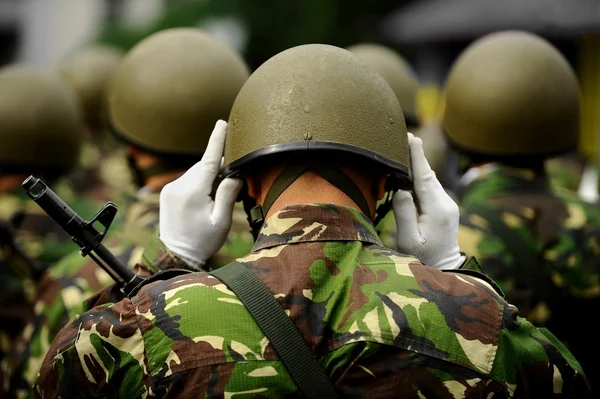 Soldier in camouflage uniform arranging his helmet — Stock Photo, Image