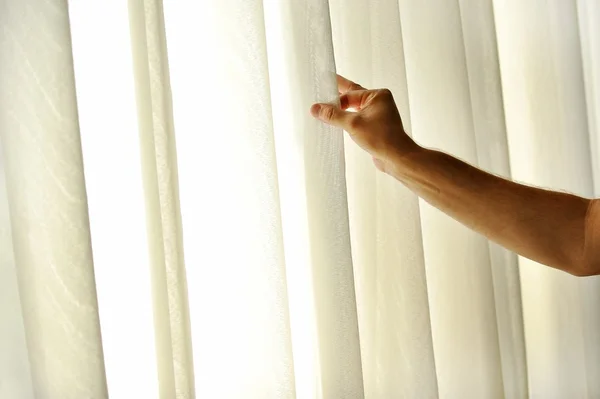 Man's hand trekken een venster gordijn — Stockfoto