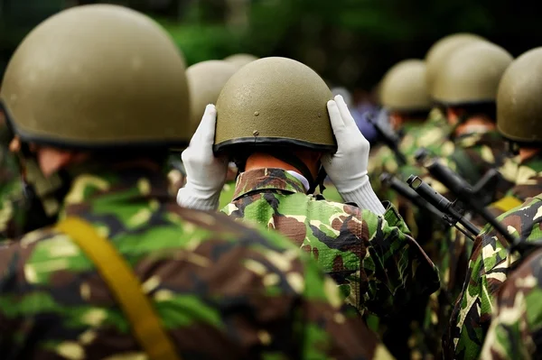 Солдат в камуфляжной форме расставляет шлем. — стоковое фото