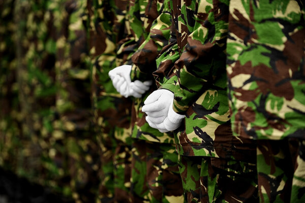 Soldiers in camouflage uniform with hands behind backs