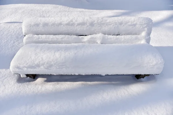 Banco em um parque coberto completamente pela neve — Fotografia de Stock