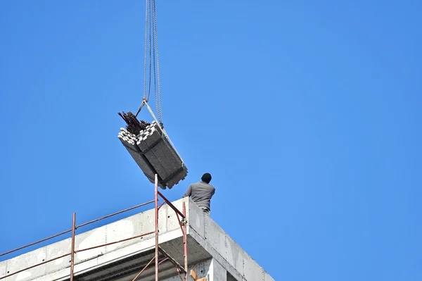 Byggnadsarbetare vägleda en konstruktion kran — Stockfoto