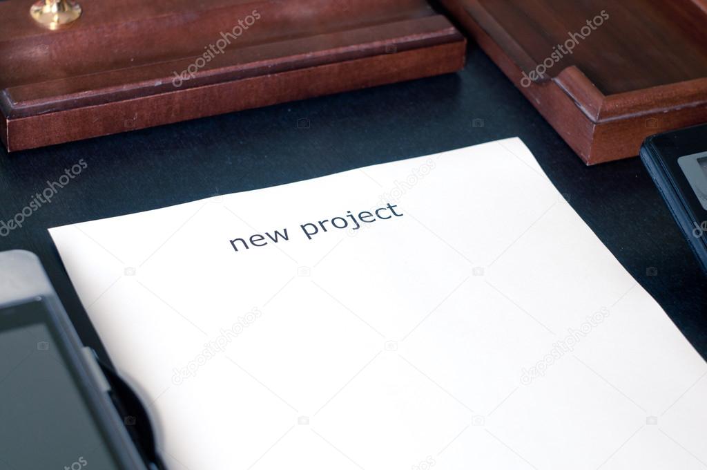 sheet of paper on a table with the word new project. Insert your text
